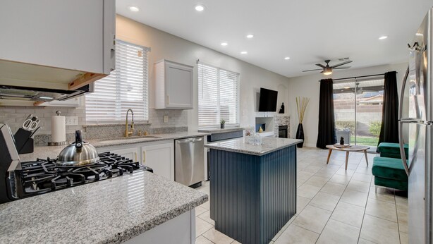 A modern kitchen with a central island, built-in appliances, and a dining area with a green sofa. - Near Las Vegas Strip and Airport: Games & Arcades- Southpoint less than 5 mins. (Las Vegas)