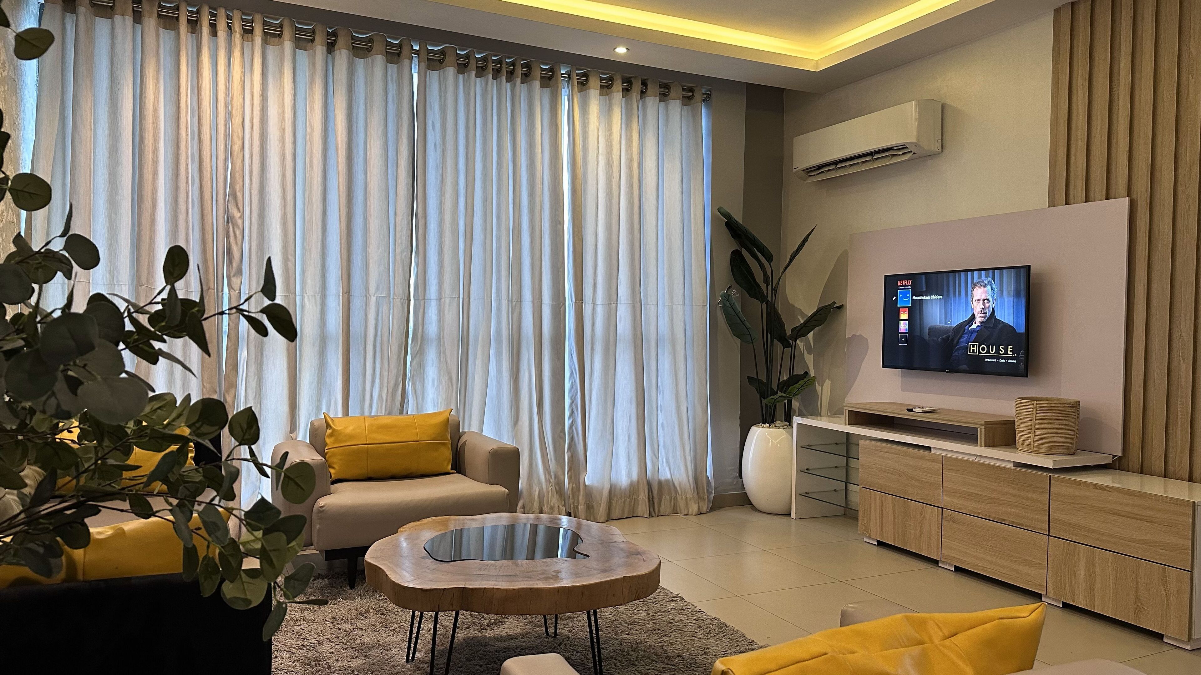 A modern living room with a sofa, coffee table, and a TV mounted on the wall.