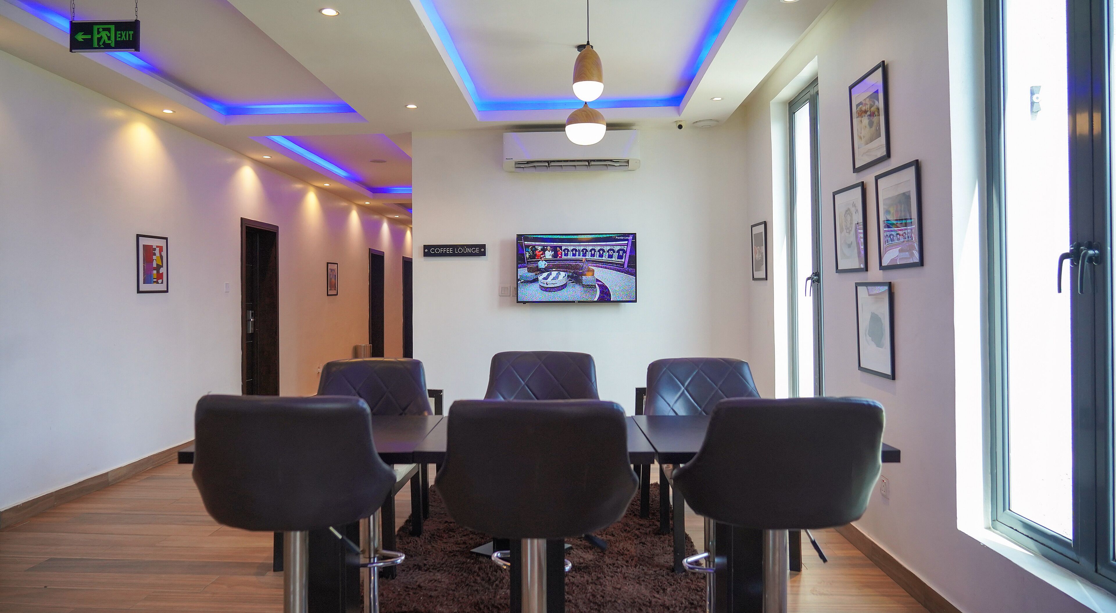 Una sala de conferencias con una televisión, cuadros enmarcados y un letrero para la sala de café.