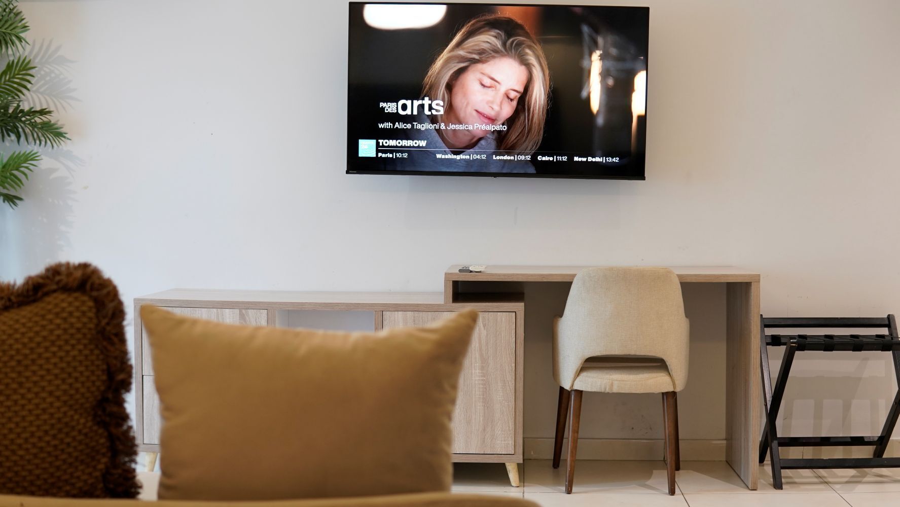 A modern living room with a television mounted on the wall displaying a program schedule.