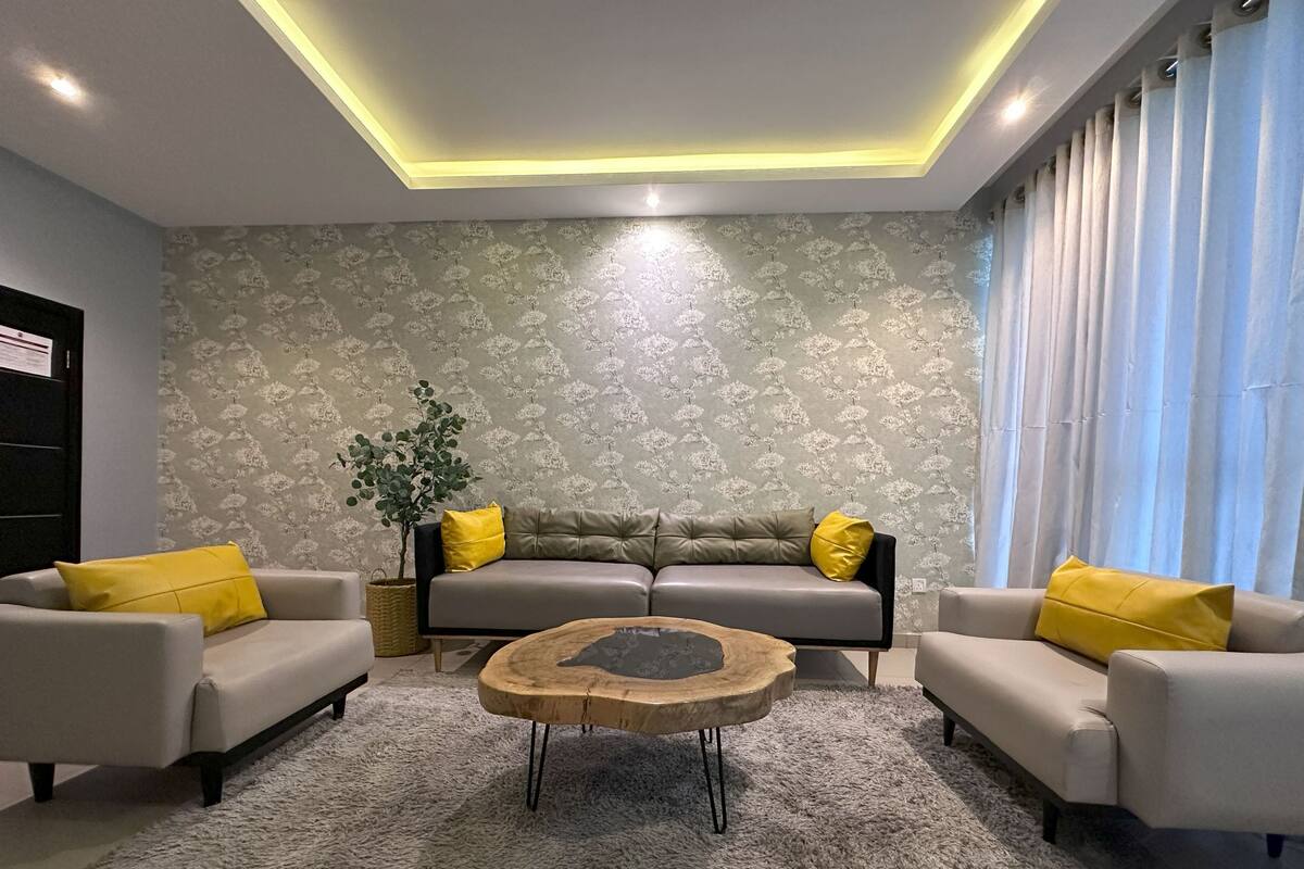 A modern living room with a sofa set, a coffee table, and a potted plant.