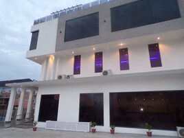 A modern two-story building with large windows, air conditioning units, and a balcony with railings.