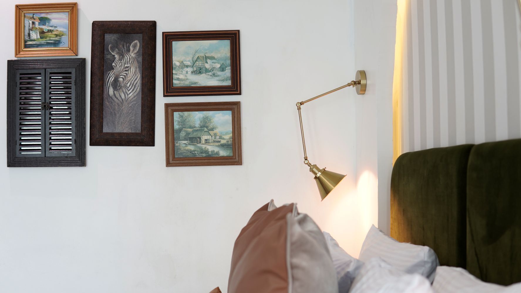 Una habitación con una cama, una lámpara de pared y tres cuadros enmarcados.