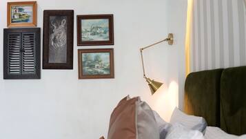 Una habitación con una cama, una lámpara de pared y tres cuadros enmarcados.