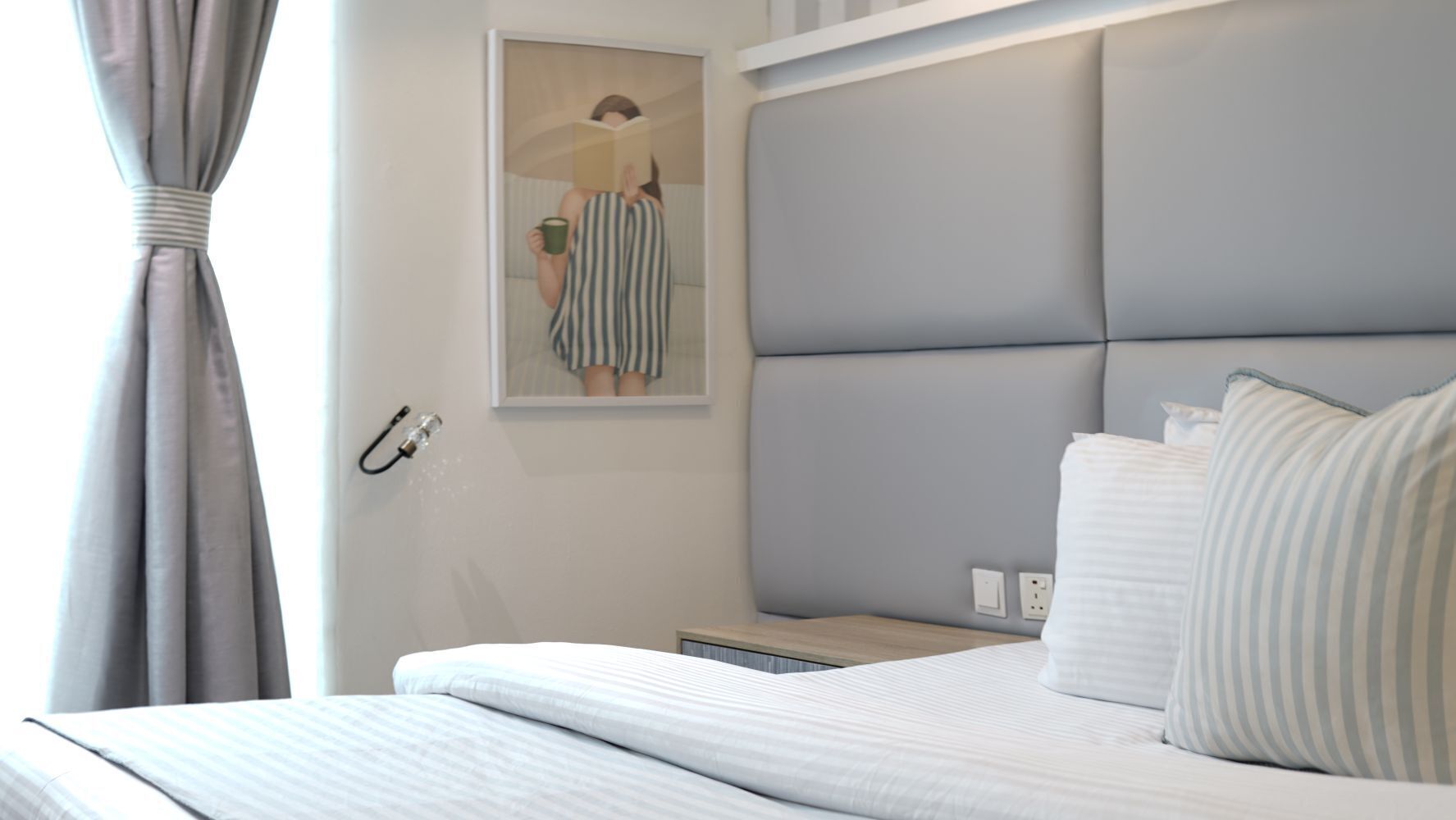 Een hotelkamer met een bed, nachtkastje, lamp en een schilderij aan de muur.