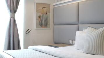 Een hotelkamer met een bed, nachtkastje, lamp en een schilderij aan de muur.