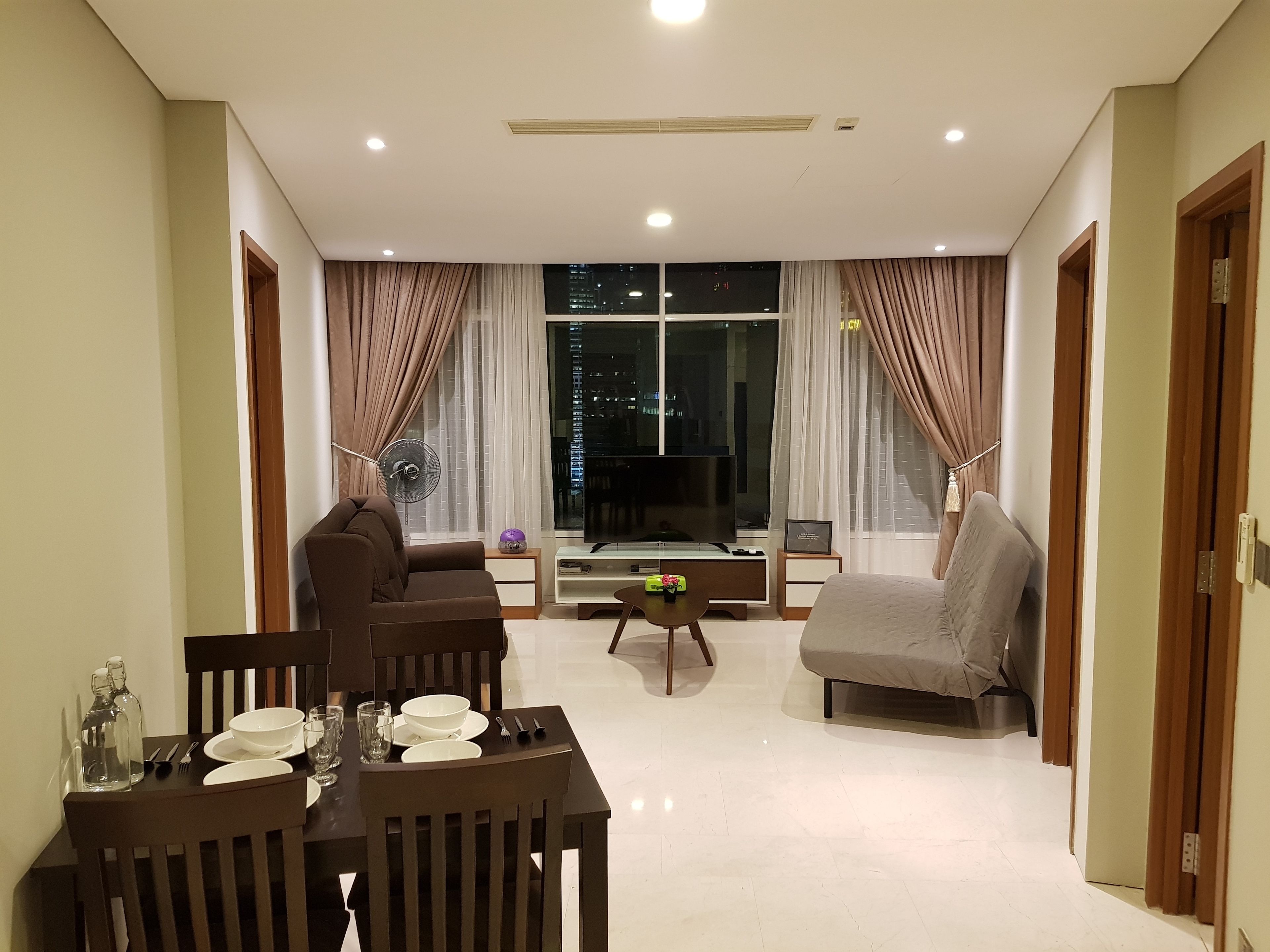 A modern living room with a sofa, a dining table set, and a TV.