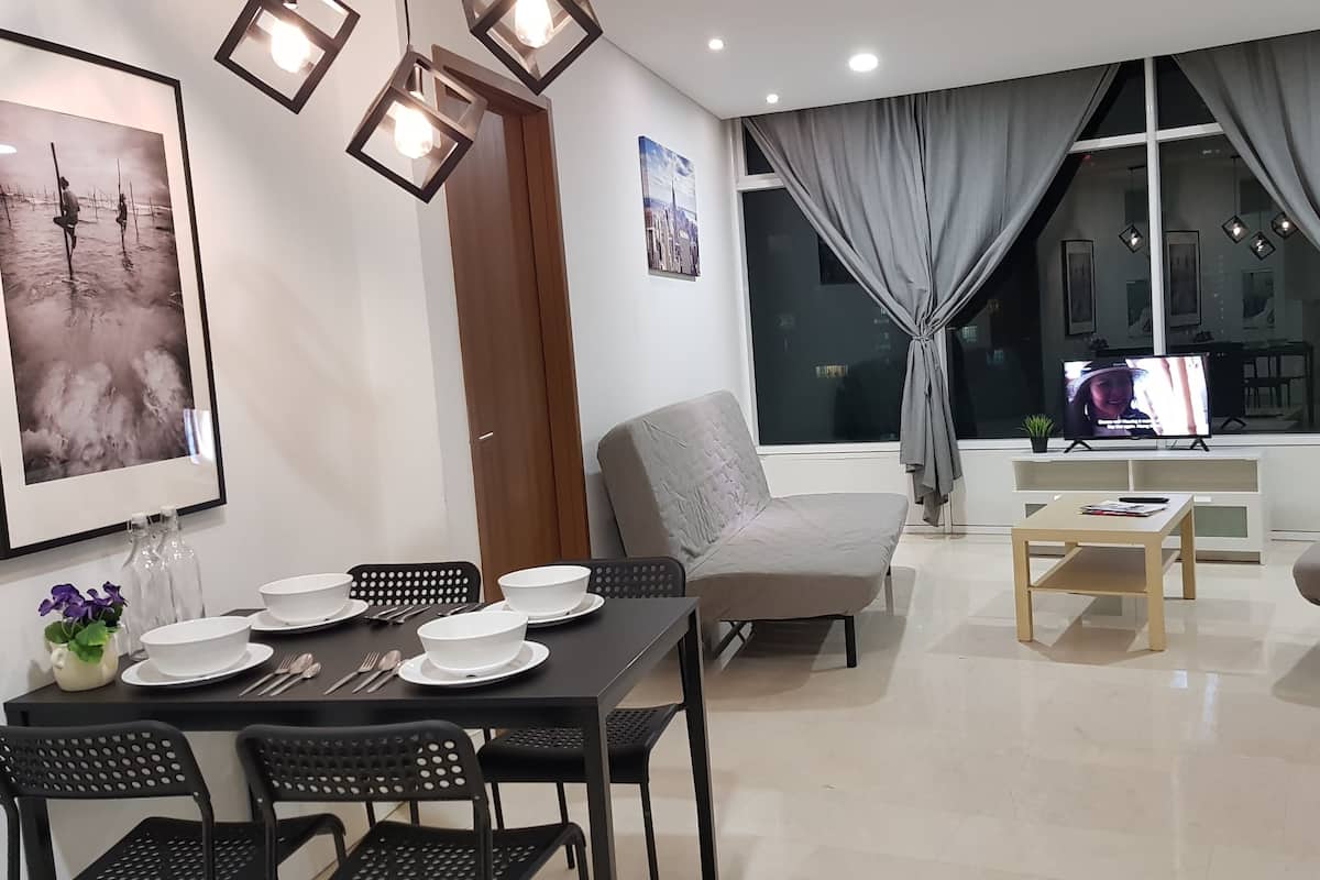 A modern living room with a dining area, featuring a sofa, a coffee table, and a TV.