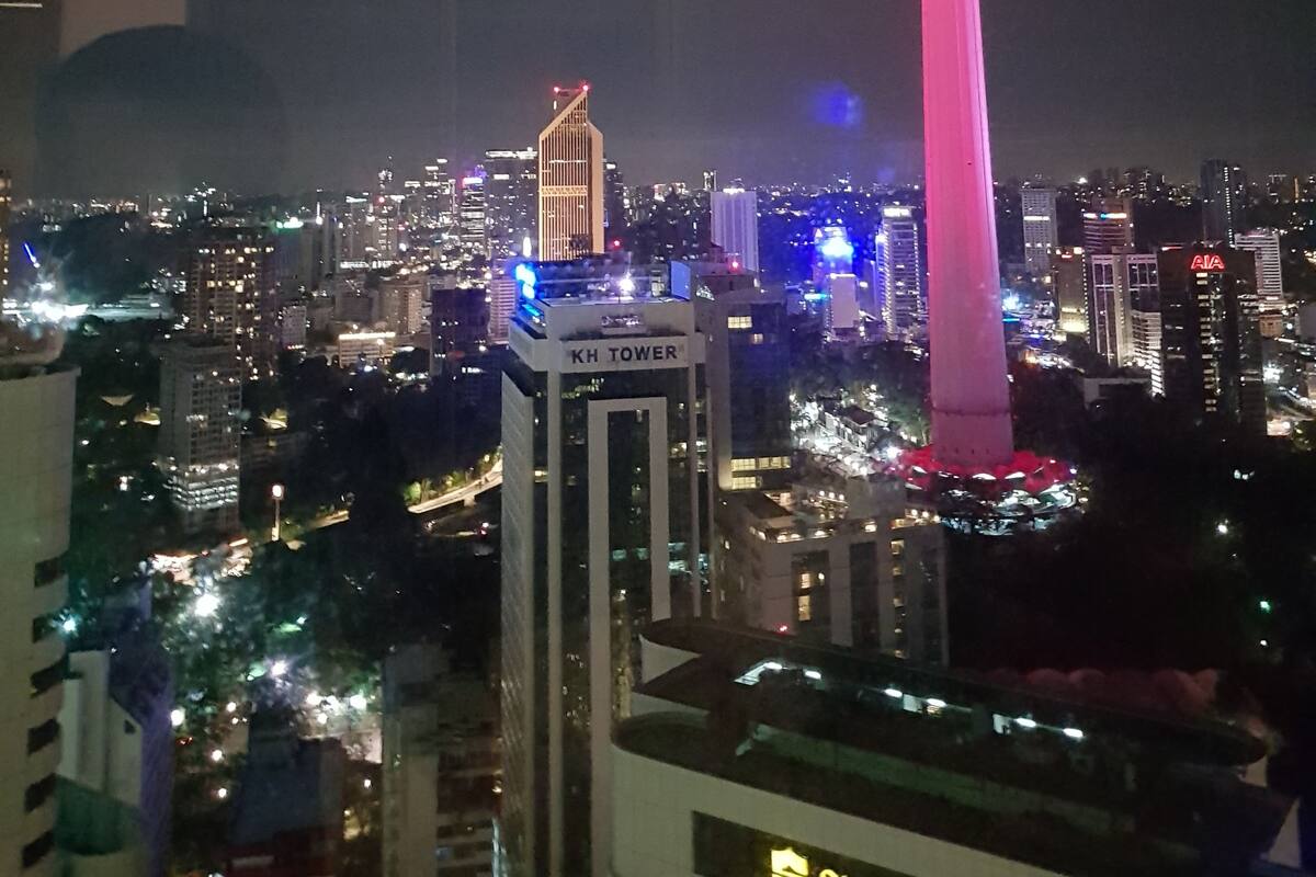 A cityscape at night with a prominent tower illuminated in pink.