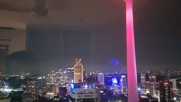 Une vue nocturne d'une ville, avec une tour imposante illuminée en rose.