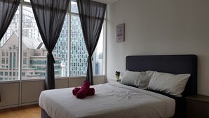 Un dormitorio con un ventanal grande, una cama con ropa de cama estampada y una frase motivacional en la pared.