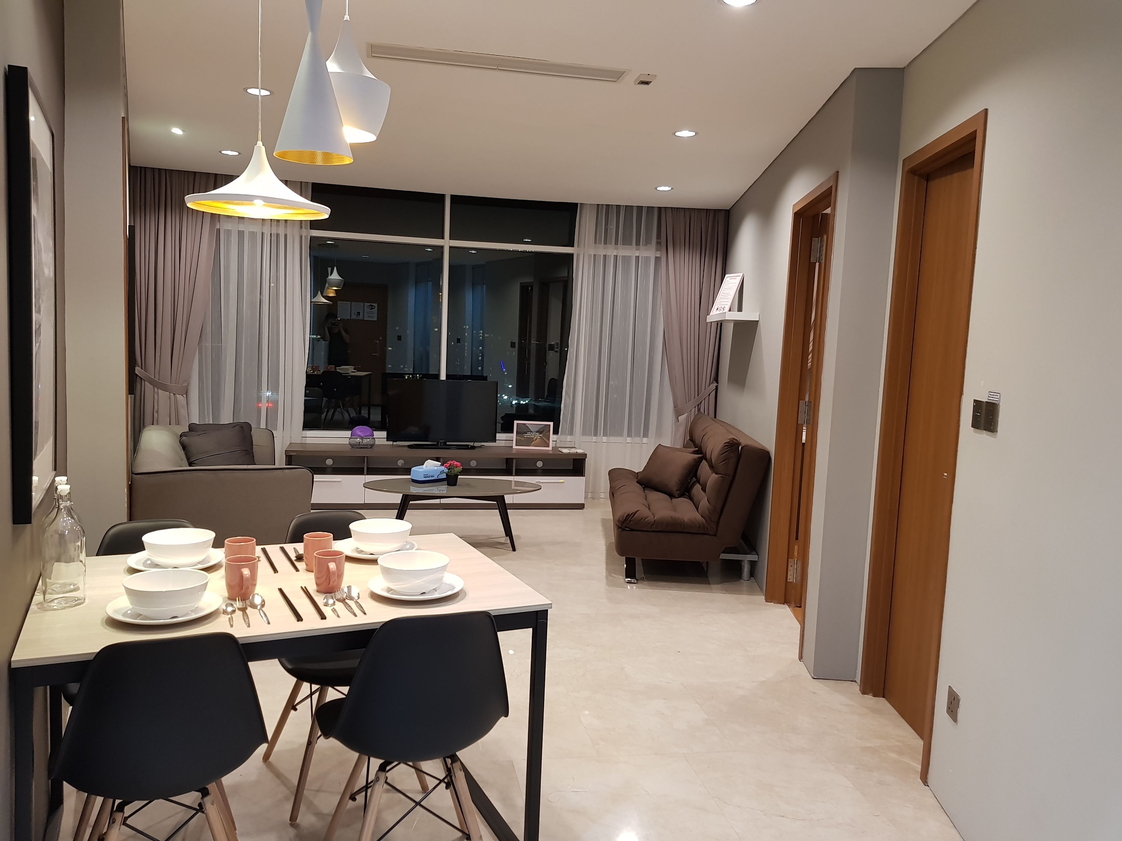 Un salon moderne avec un coin repas, de grandes fenêtres et une vue sur la ville.