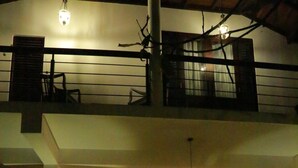 A spacious interior with a staircase leading to an upper level, a dining area with tables and chairs, and pendant lighting. - Midigama Holiday Inn (Ahangama)