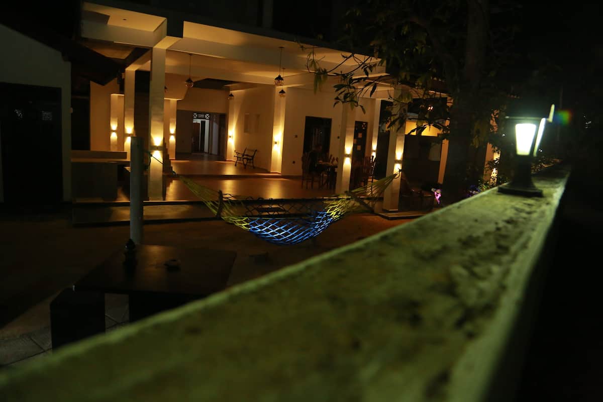 A hammock in a dimly lit outdoor area with a bench and a lamp post.
