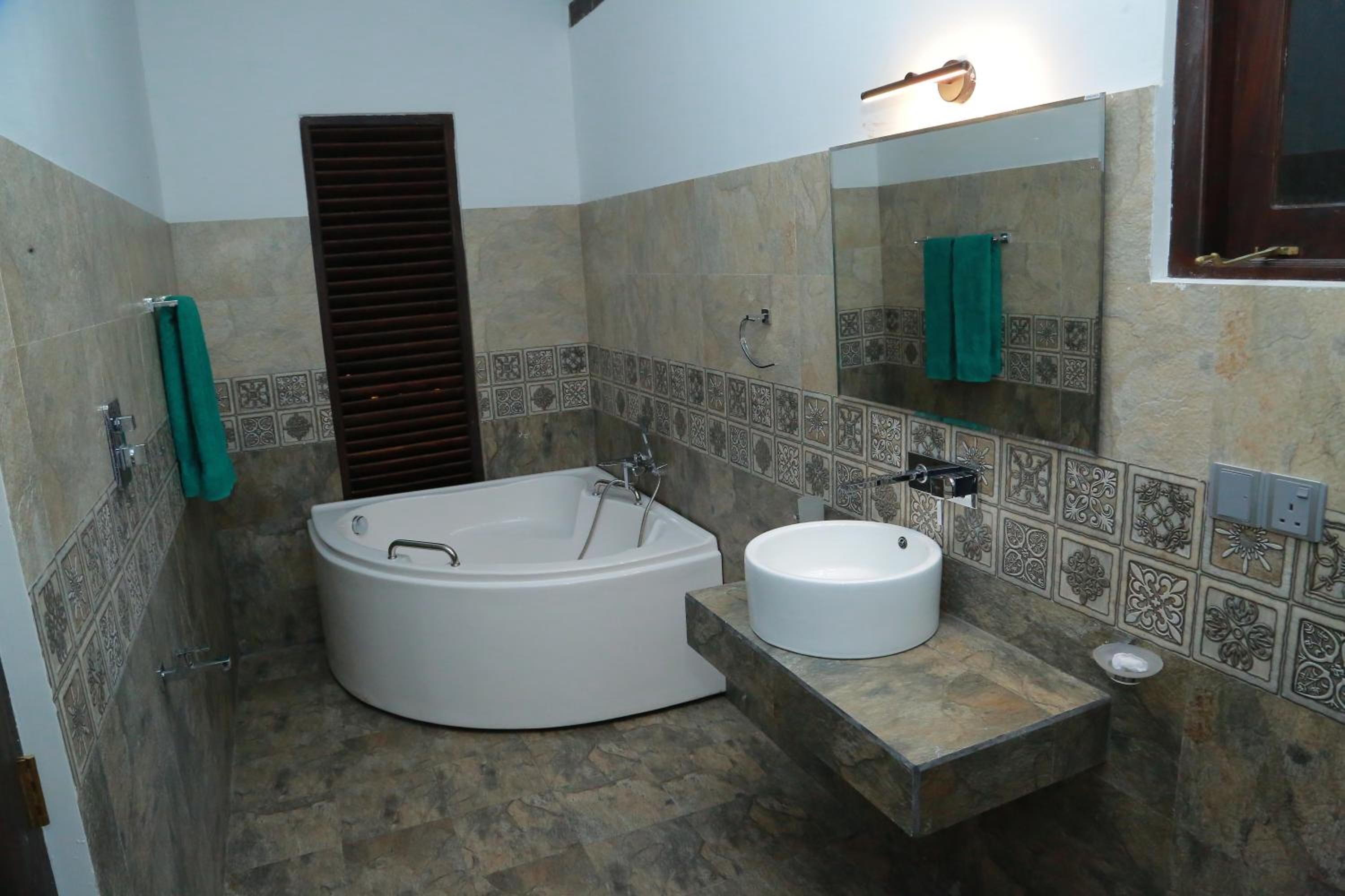 A bathroom with a freestanding bathtub, a round sink, and a large mirror.