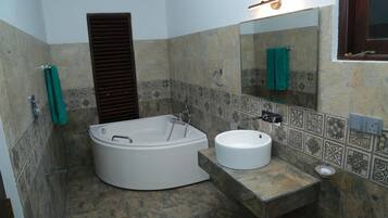 A bathroom with a freestanding bathtub, a round sink, and a large mirror.