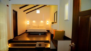 A bedroom with a bed, bedside lamps, a small table, and a door. - Midigama Holiday Inn (Ahangama)