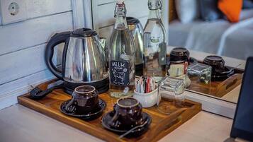 A wooden tray with a coffee maker, a milk bottle, and various cups and mugs.