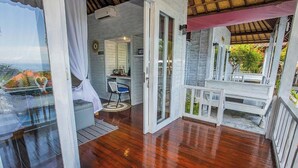 Eine Holterrasse mit einer Glastür, die zu einem Zimmer mit einem Bett und einem Stuhl führt.