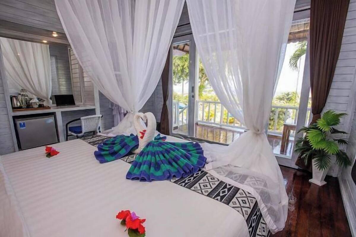 A bedroom with a bed, a desk, and a view of the outdoors.