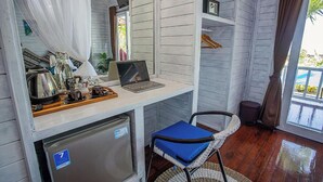 Ein kleines Zimmer mit Schreibtisch, Laptop und kleinem Kühlschrank.