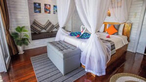 Ein Schlafzimmer mit einem Bett, einer Bank, einer Topfpflanze und Kunstwerken an der Wand.