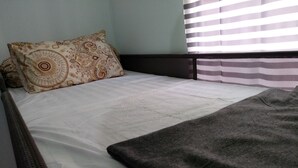 A bed with a patterned pillow, a plain white bedsheet, and a grey blanket. - RJB at Ayodhya Tangerang (Tangerang)