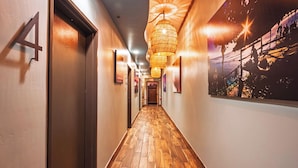 A hallway with wooden flooring, a number '4' sign, and a large framed picture on the right wall. - Nomads Hotel - Near San Clemente Pier (San Clemente)