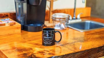 Eine Küchenarbeitsfläche mit Kaffeemaschine, Tasse, Glasbehälter und Spüle.