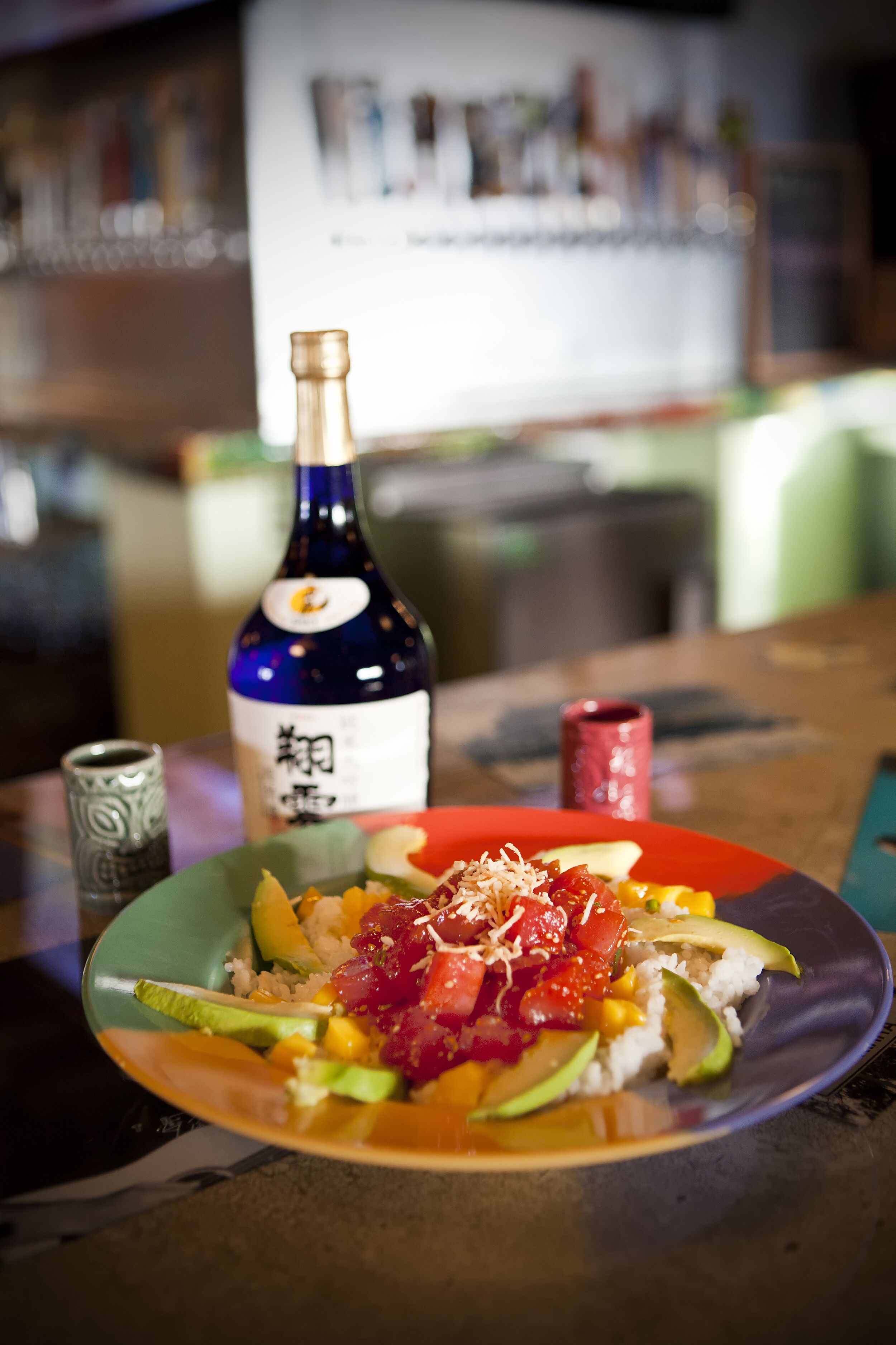 A plate of sushi with a bottle of sake and a small cup on a table.