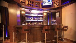 Zona de bar con mostrador de madera, cuatro taburetes de bar y un televisor montado sobre el mostrador.