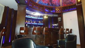 Zona de bar con techo de vitrales, taburetes y una barra bien surtida.