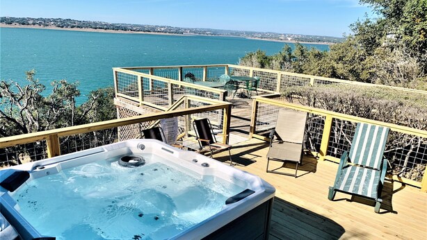 Un jacuzzi en una terraza de madera con vista al mar.