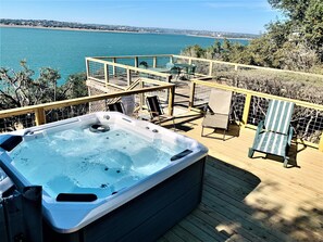 A hot tub on a wooden deck with a view of the sea.