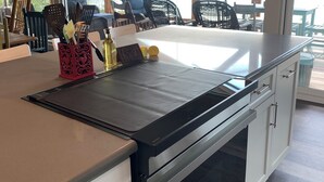 Una cocina con una isla grande, electrodomésticos de acero inoxidable y vistas a una terraza con mobiliario exterior.