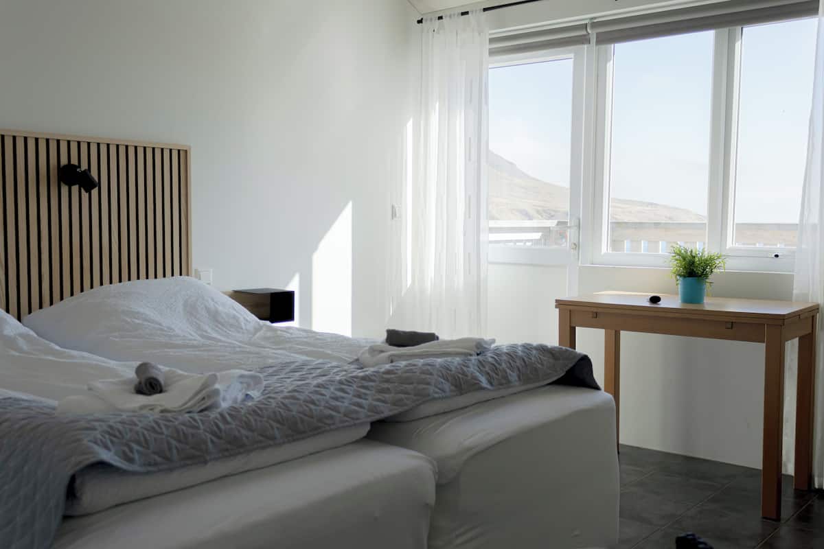 Un dormitorio con cama, mesita de noche y ventana con vistas.