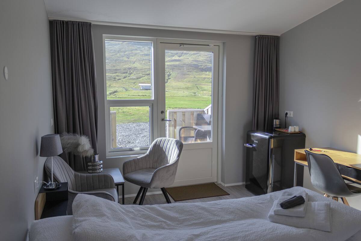 Habitación de hotel con cama, escritorio, silla, televisión y vistas al exterior.