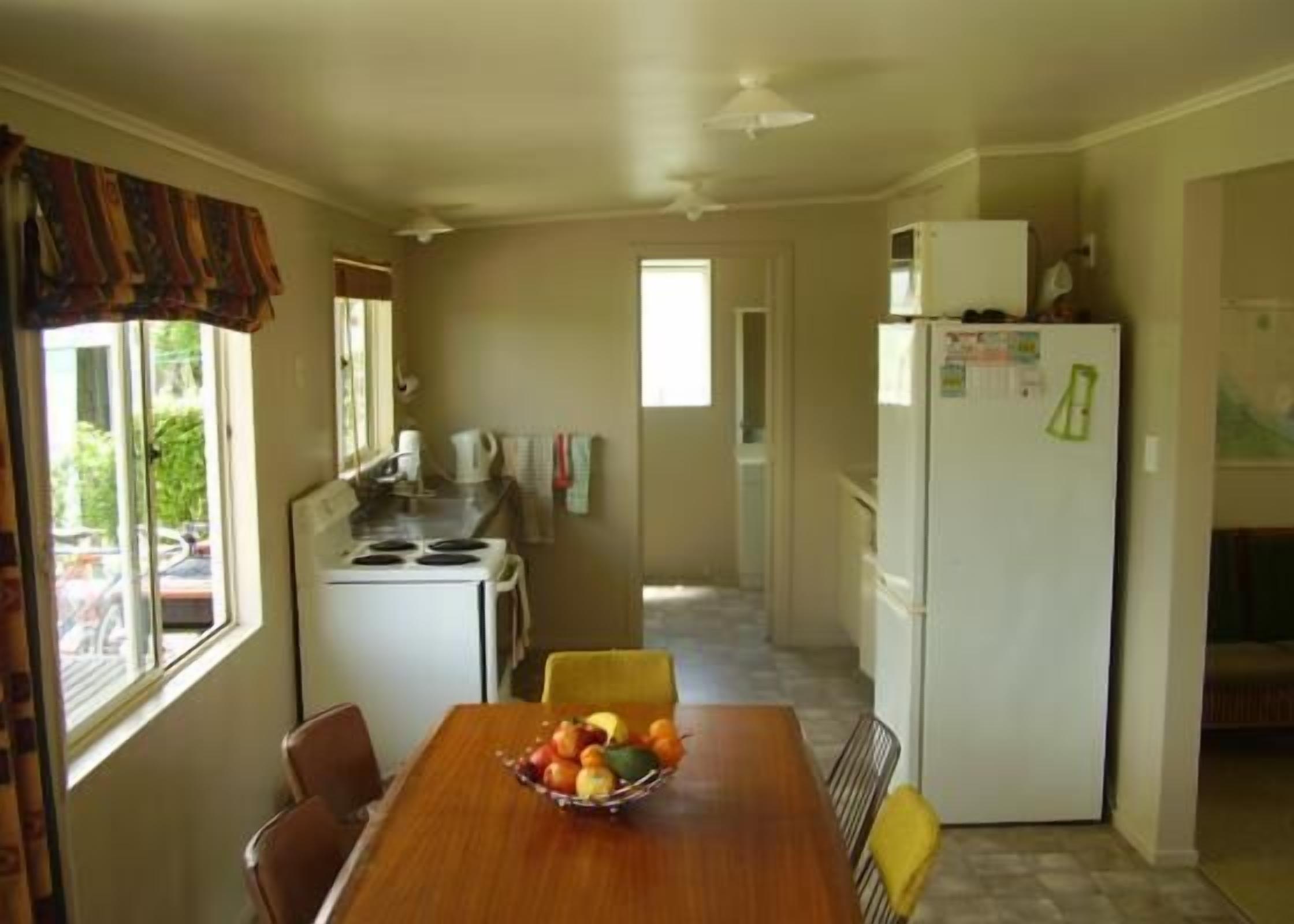 A compact kitchen with a dining table set for two, a refrigerator, and a stove.