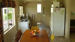 Una cocina compacta con una mesa de comedor para dos personas, un refrigerador y una estufa.