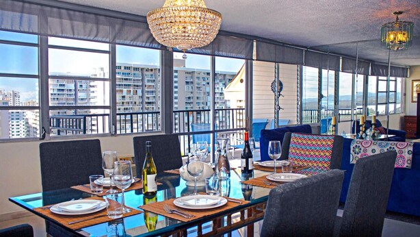 A dining area with a table set for two, large windows offering a city view, and a chandelier. - tlLuxury Penthouse Oasis, Steps to the Beach, Spacious, Pool & Near Dining (Carolina)