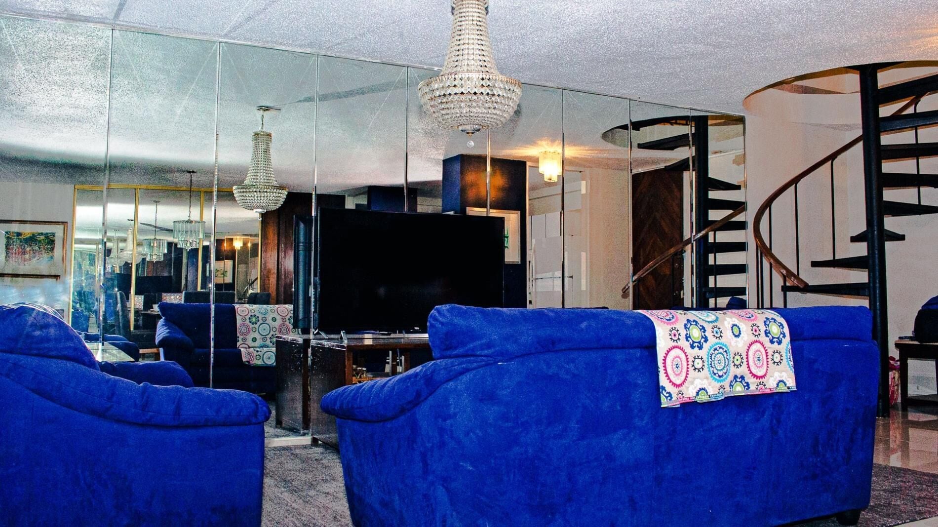 Un salon avec des canapés bleus, un téléviseur et un lustre.