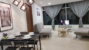 A modern living room with a dining area, featuring a sofa, a coffee table, and a TV. - SUPER VALUE APARTMENT near KLCC Twin Tower/ KL City Centre (Kuala Lumpur)