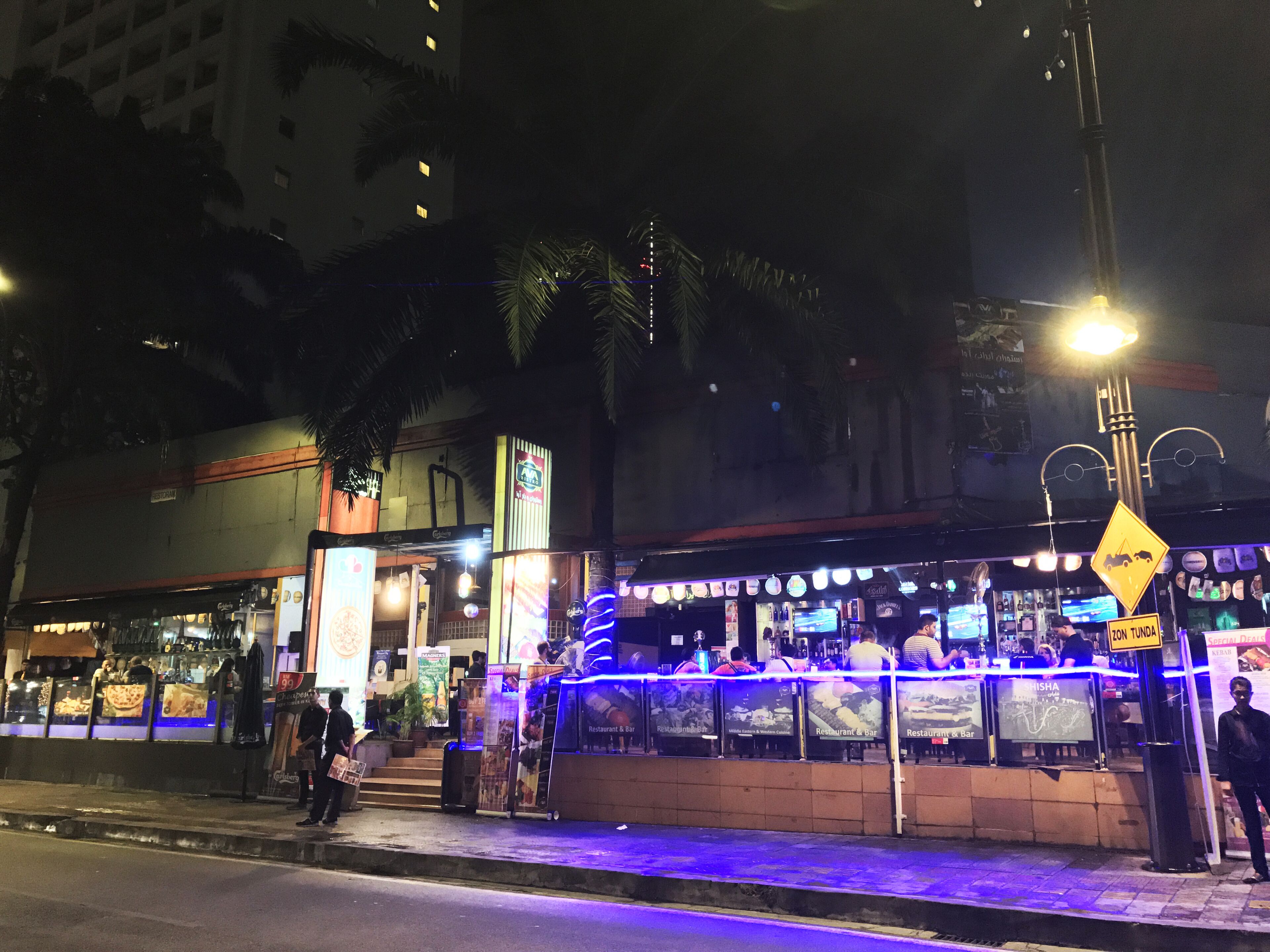 A nighttime street scene with a bar and restaurant.