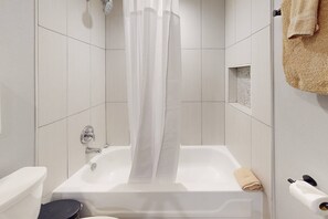 Een bad/douchecombinatie, een haardroger, handdoeken