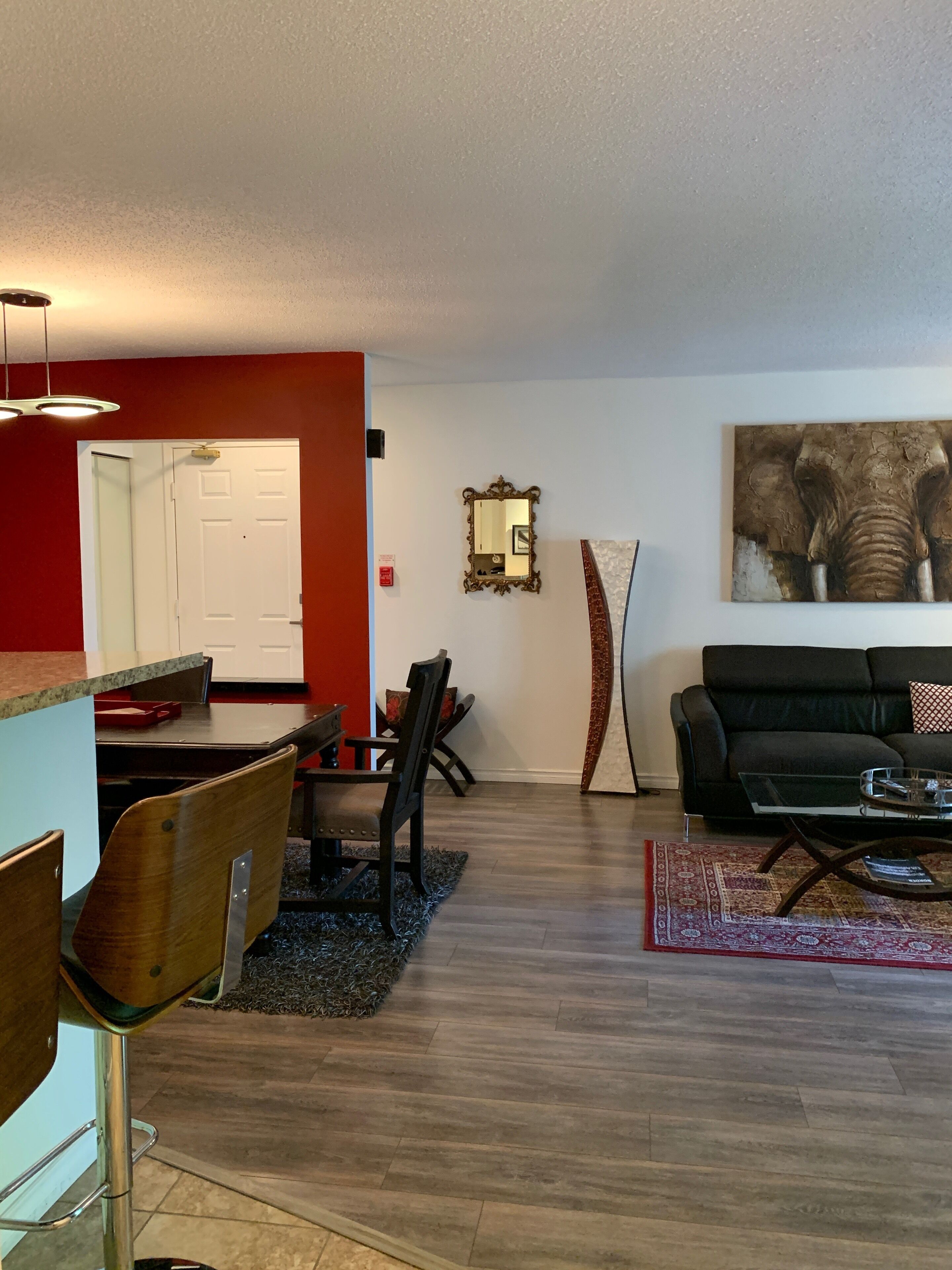 Ein modernes Wohnzimmer mit einer schwarzen Couch, einem Couchtisch und einem Essbereich mit Holztischen und Stühlen.