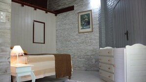 Une chambre à coucher avec un lit, une table de chevet avec une lampe, une commode, un tableau encadré au mur et un tapis à motifs.