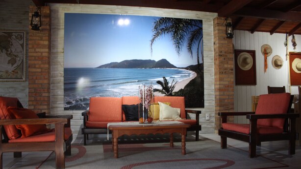 Un salon avec une grande fresque murale représentant une plage, un canapé, deux fauteuils, une table basse et une cheminée.