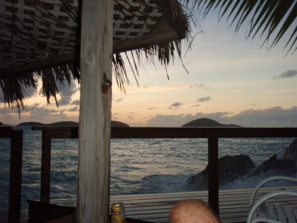 A wooden deck with a thatched roof overlooking the sea. - Casa Jo Mama so private clothing is optional!! (St. Thomas)
