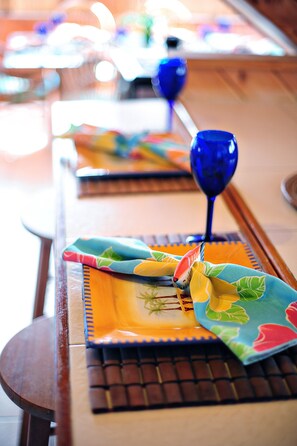 Een houten tafel met een blauw glas en een kleurrijke servet.