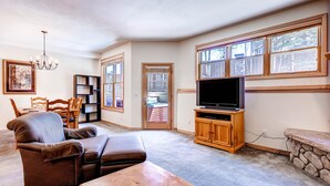 A living room with a television, a sofa, a coffee table, and a bookshelf.